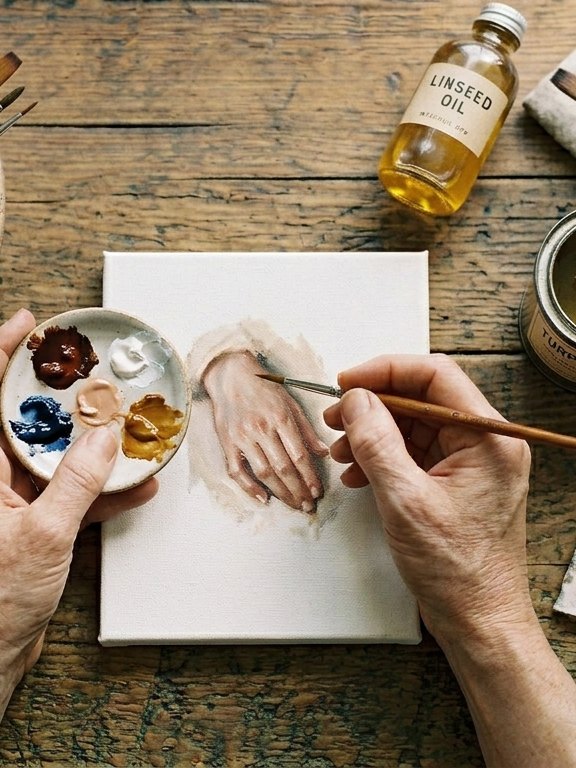Manos pintando al óleo sobre un lienzo pequeño